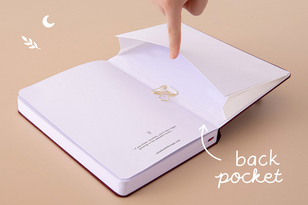 Open back page pocket of Tsuki ‘Kinoko’ Limited Edition Bullet Journal held in hand with free paperclip gift on beige background