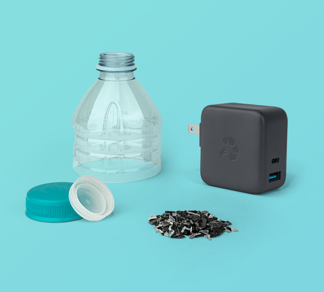 Wall charger displayed alongside a water bottle, caps, and recycled plastic pieces.