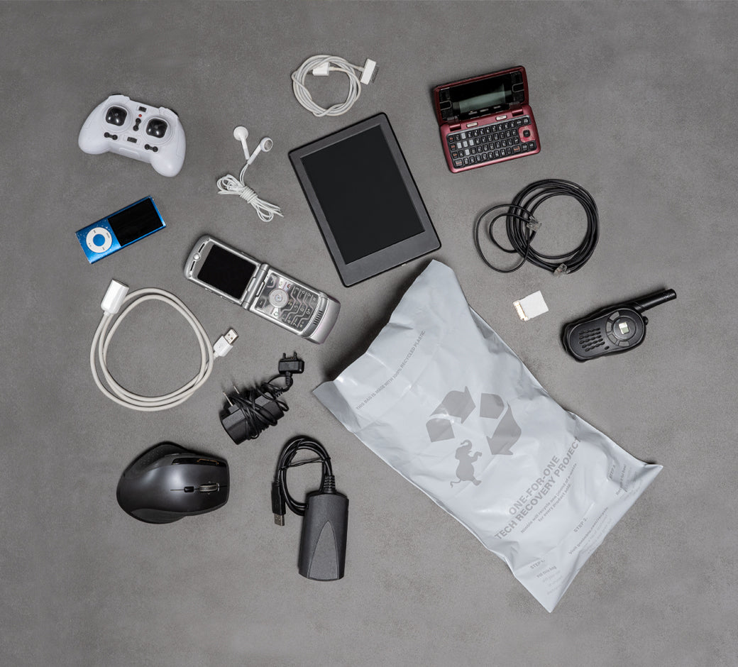 Collection of old electronics and accessories for recycling, including a tablet, cables, and a game controller.