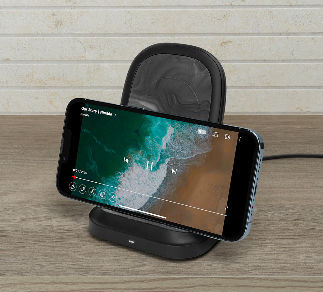 Phone on a horizontal wireless stand playing a video, displayed on a wooden surface.