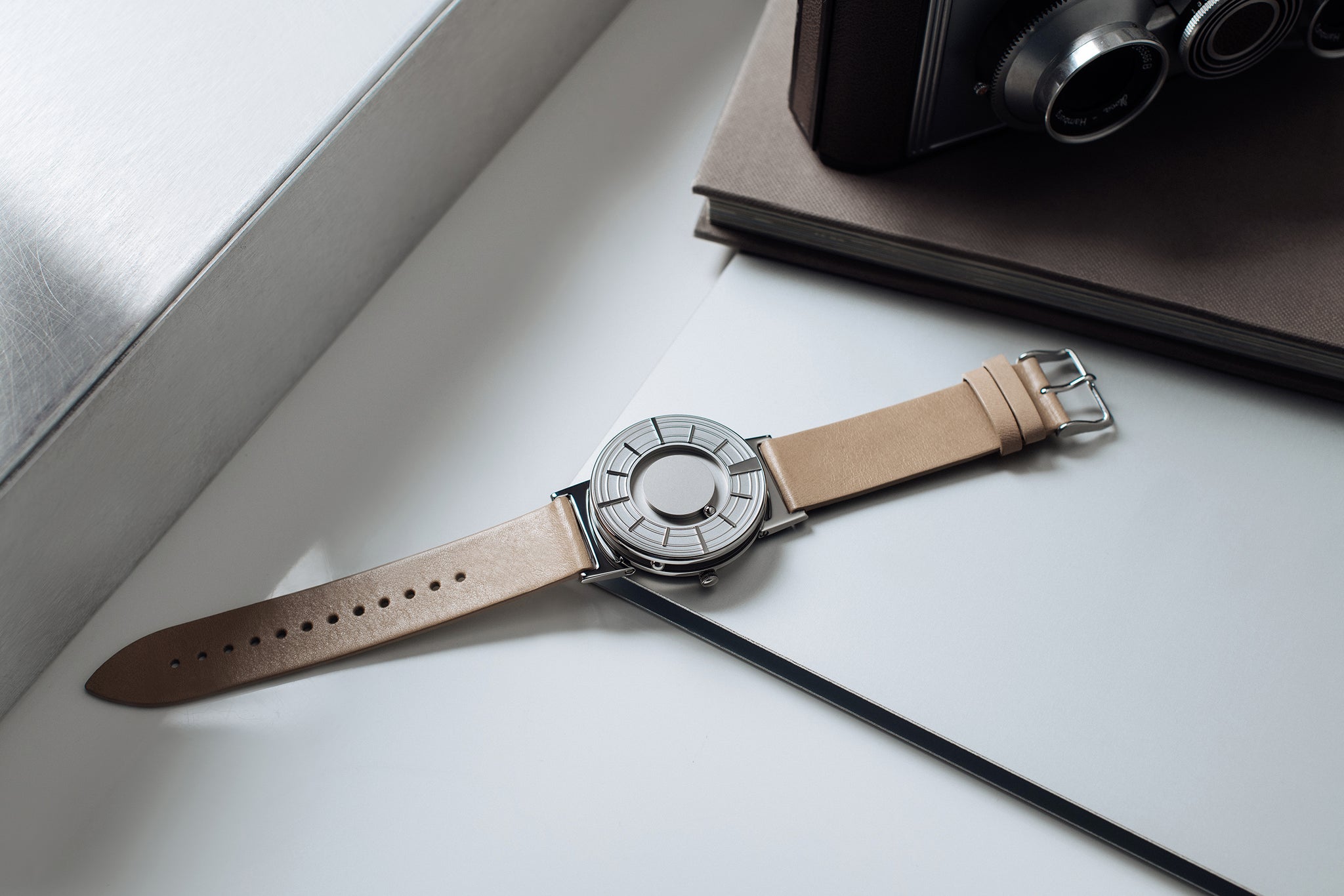 The Bradley Edge Silver is flat on a white surface. There is a small brown book in the top right corner of the image.