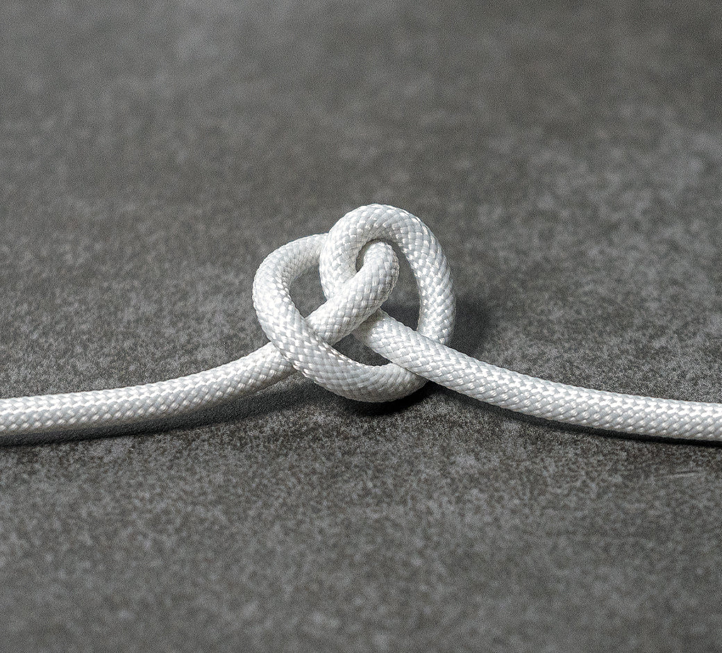 White cable tied in a knot on a dark slate surface.