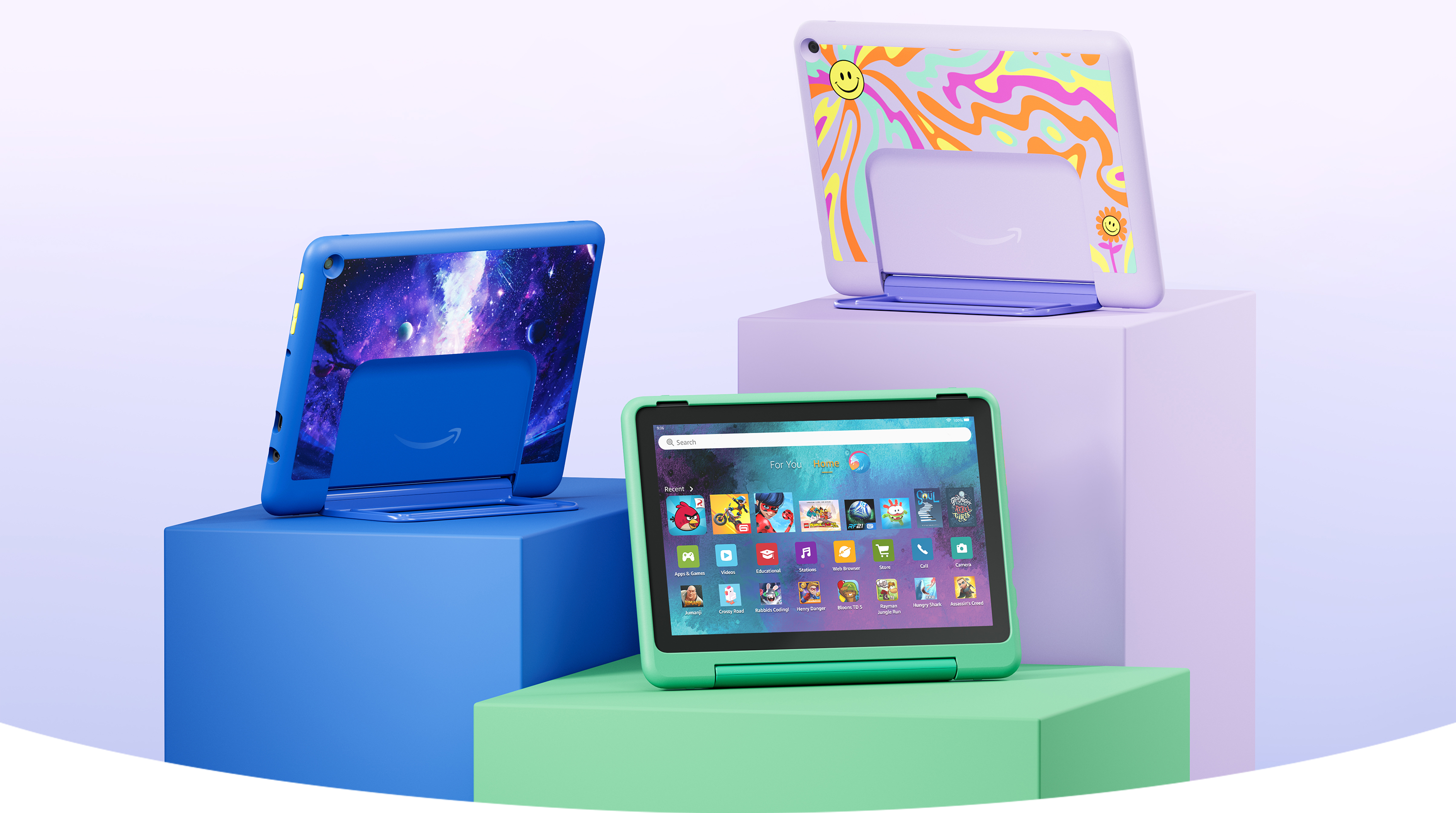 Three Fire HD 10 Kids Pro tablets on pedestals of varying heights showcasing three color options (from left to right): Blue with a galaxy print, green, and purple with a sunburst pattern.