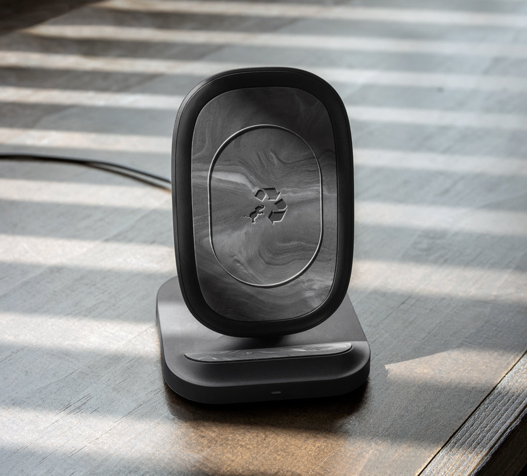 Black marbled wireless stand positioned on a table, illuminated by sunlight through blinds.