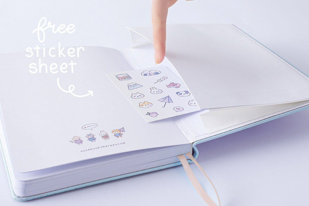 Close up of the back page pocket of Tsuki ‘Four Seasons: Autumn Edition’ Bullet Journal made with milkkoyo held in hand with free sticker sheet on lilac background