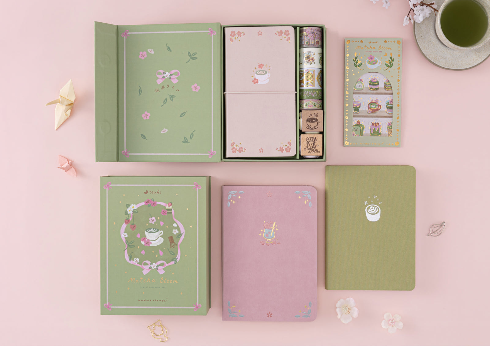 An open Matcha Bloom notebook decorated with themed stickers and washi tape next to a cup of green tea.