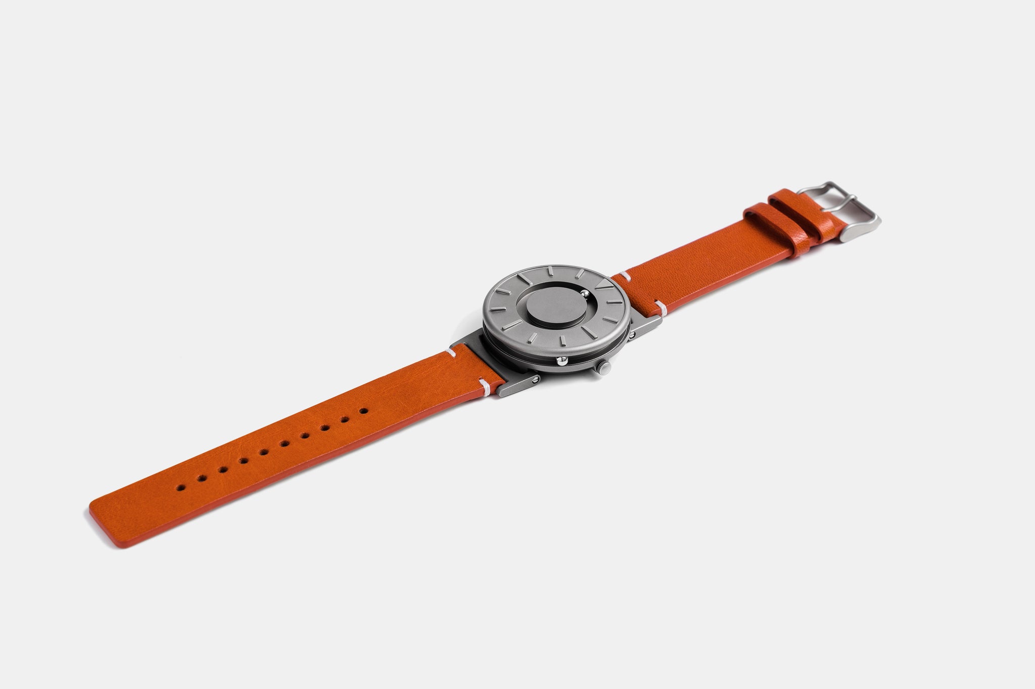 A photo of the watch lying flat on a surface. The recessed track around the outside of the watch face is shown with the hour ball bearing in the track. The raised markers are noticeable from this perspective.