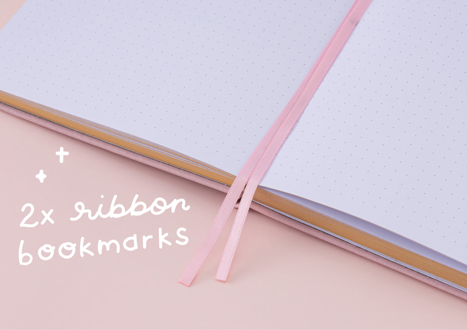 An open view of the dot grid notebook pages featuring two slim pink ribbon bookmarks.