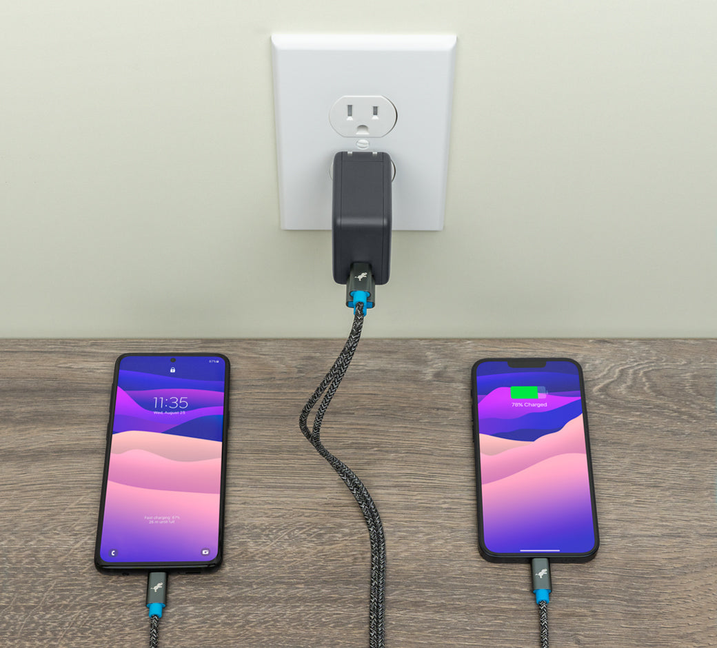 Two smartphones charging side-by-side, connected to a dual-port wall charger.