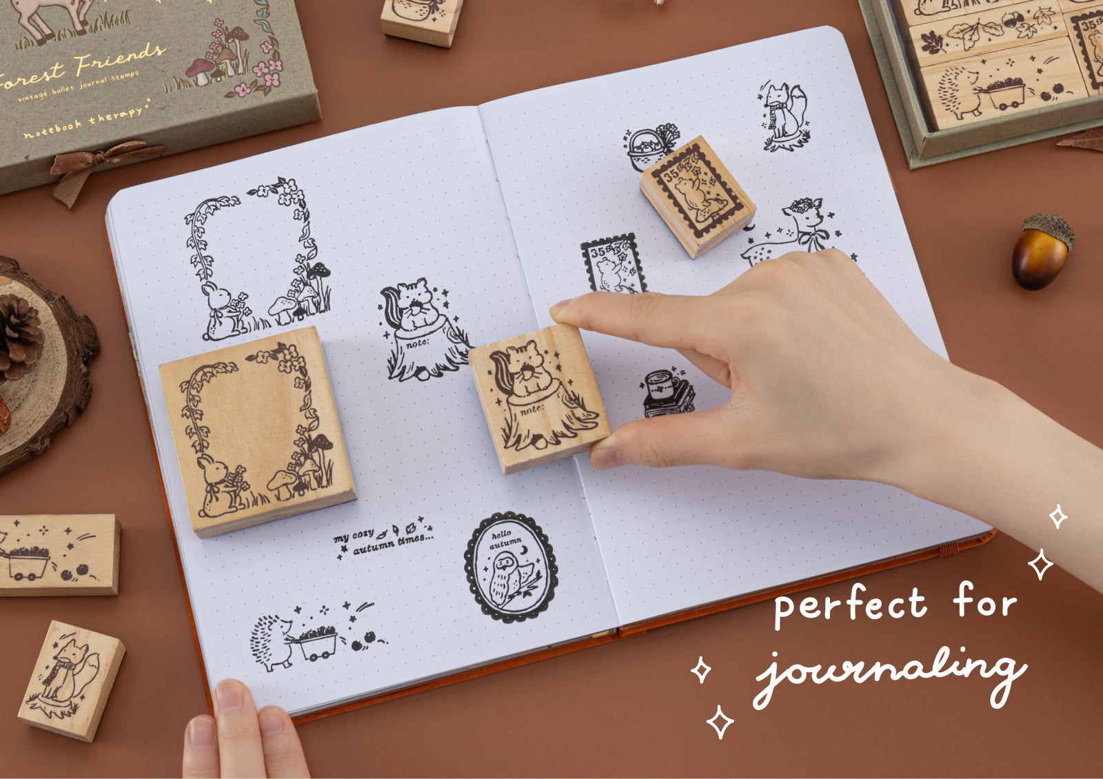Hand stamping Forest Friends designs in a dotted journal, featuring a squirrel and nature-inspired frames.