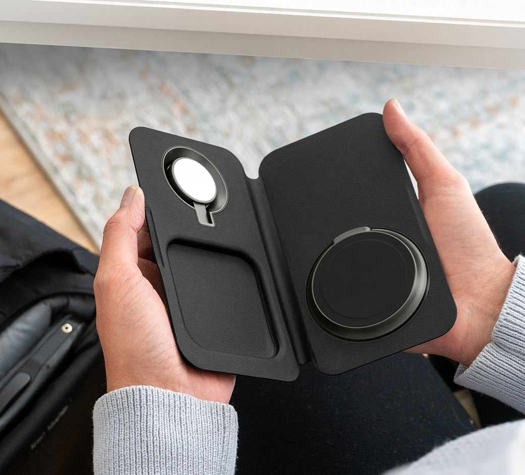 A person holding a black phone case with MagSafe charging support.