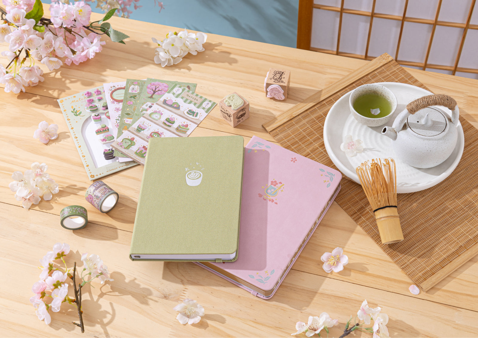 A lifestyle flat lay featuring the notebooks, stickers, washi tape, and a traditional Japanese matcha tea set.