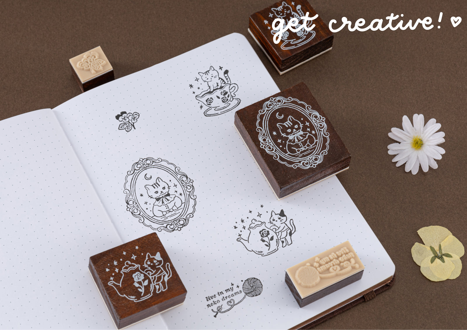 A close-up of different cat stamp impressions in a journal with the text 'get creative!', highlighting the fine detail of the wooden stamps.
