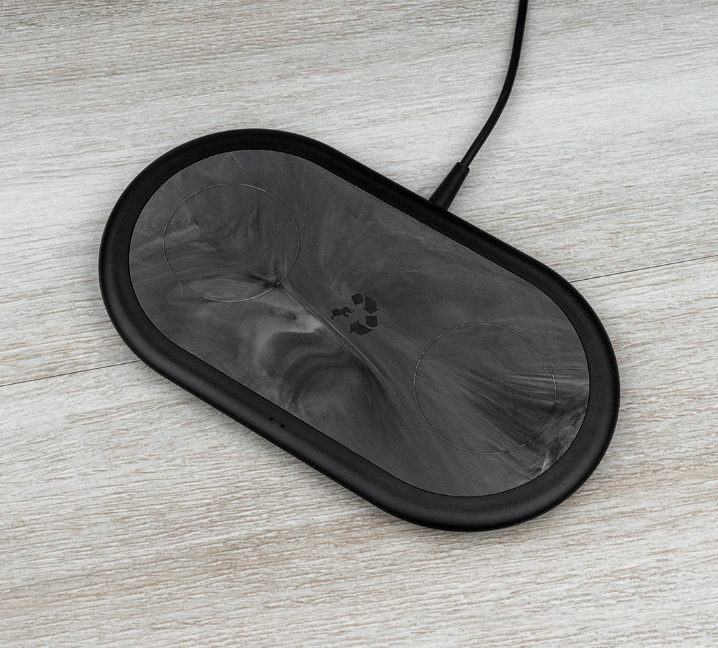 Black marbled charging pad on a light wooden surface.