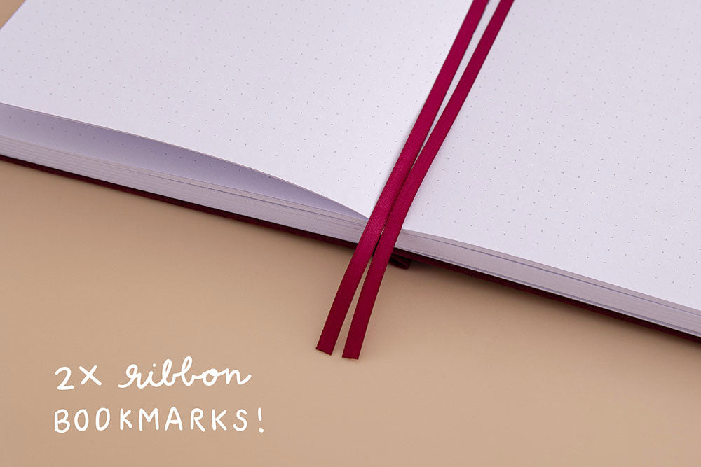 Open page spread of Tsuki ‘Kinoko’ Limited Edition Bullet Journal with two bookmark ribbons on beige background