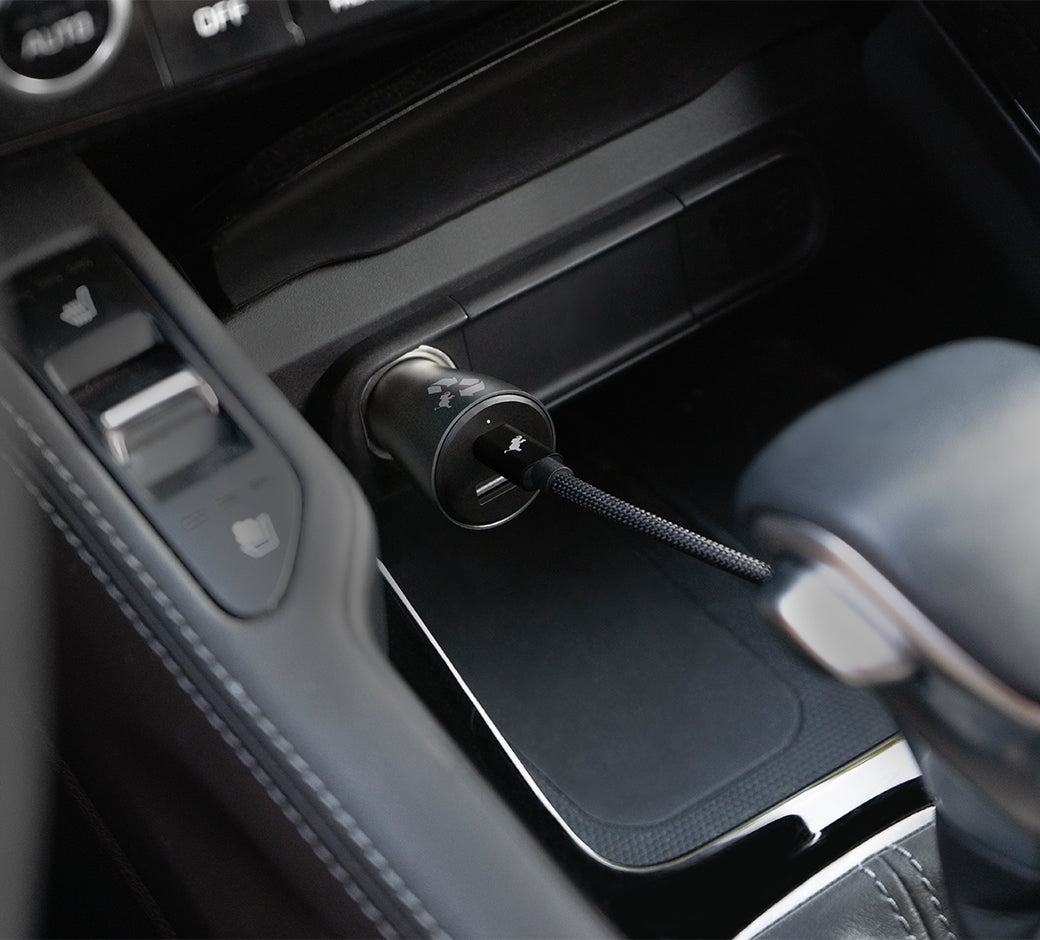 Car charger plugged into vehicle console, charging a device.