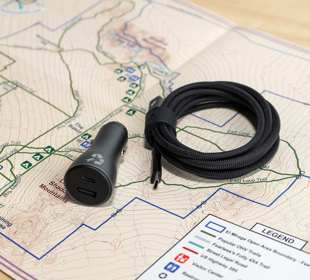 Car charger and USB cable on a map, ready for travel.
