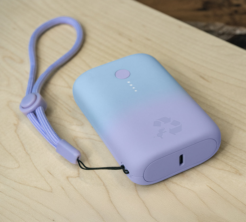 A blue portable battery pack with a wrist strap on a wooden surface.