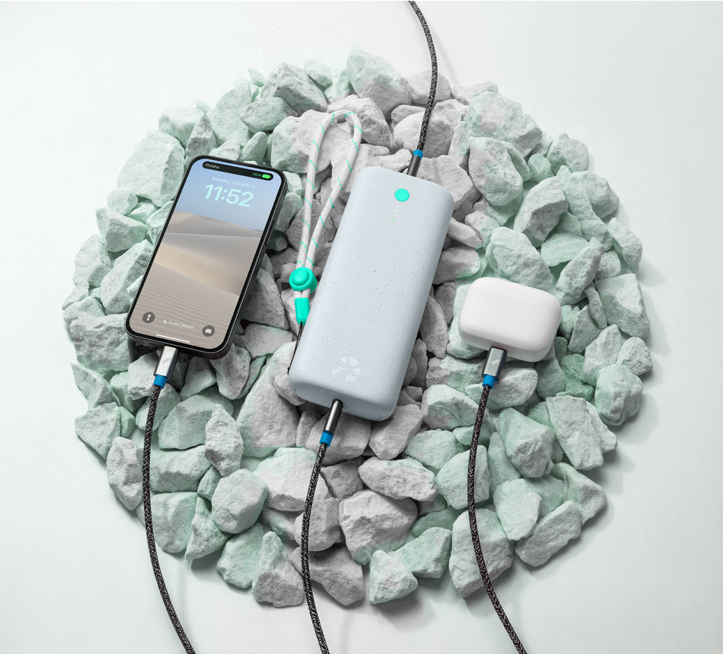 White power bank charging devices on smooth green and white stones.