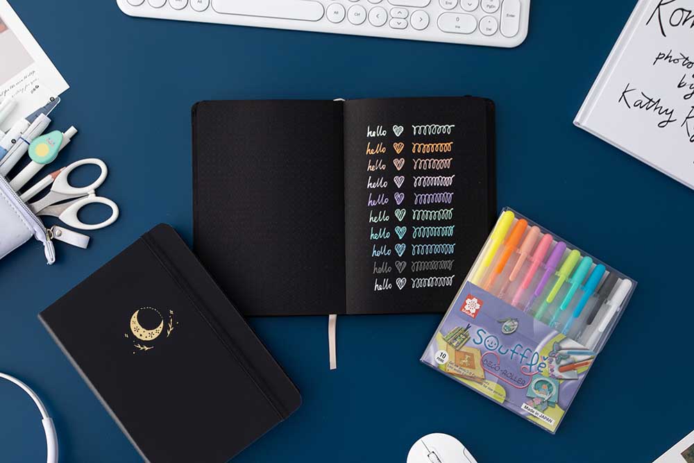 Open Tsuki Black Paper Limited Edition Hardcover Bullet Journal with black page Moonflower edition notebook with Rainbow Gelly Soufflé pens with keyboard and Tsuki Pop-Up Pencil Case on dark blue background