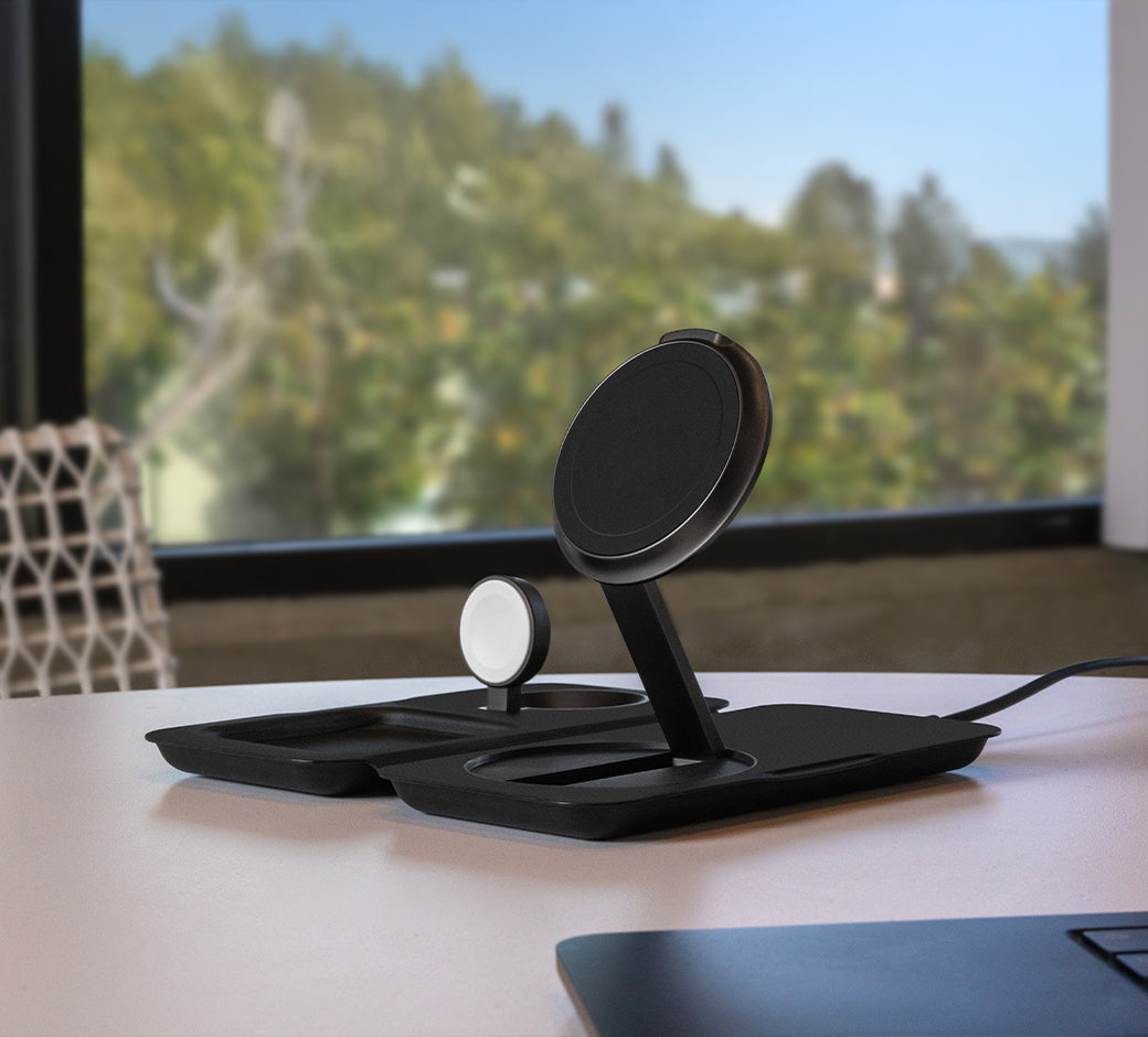 A dual charging station with a phone and AirPods on a desk.