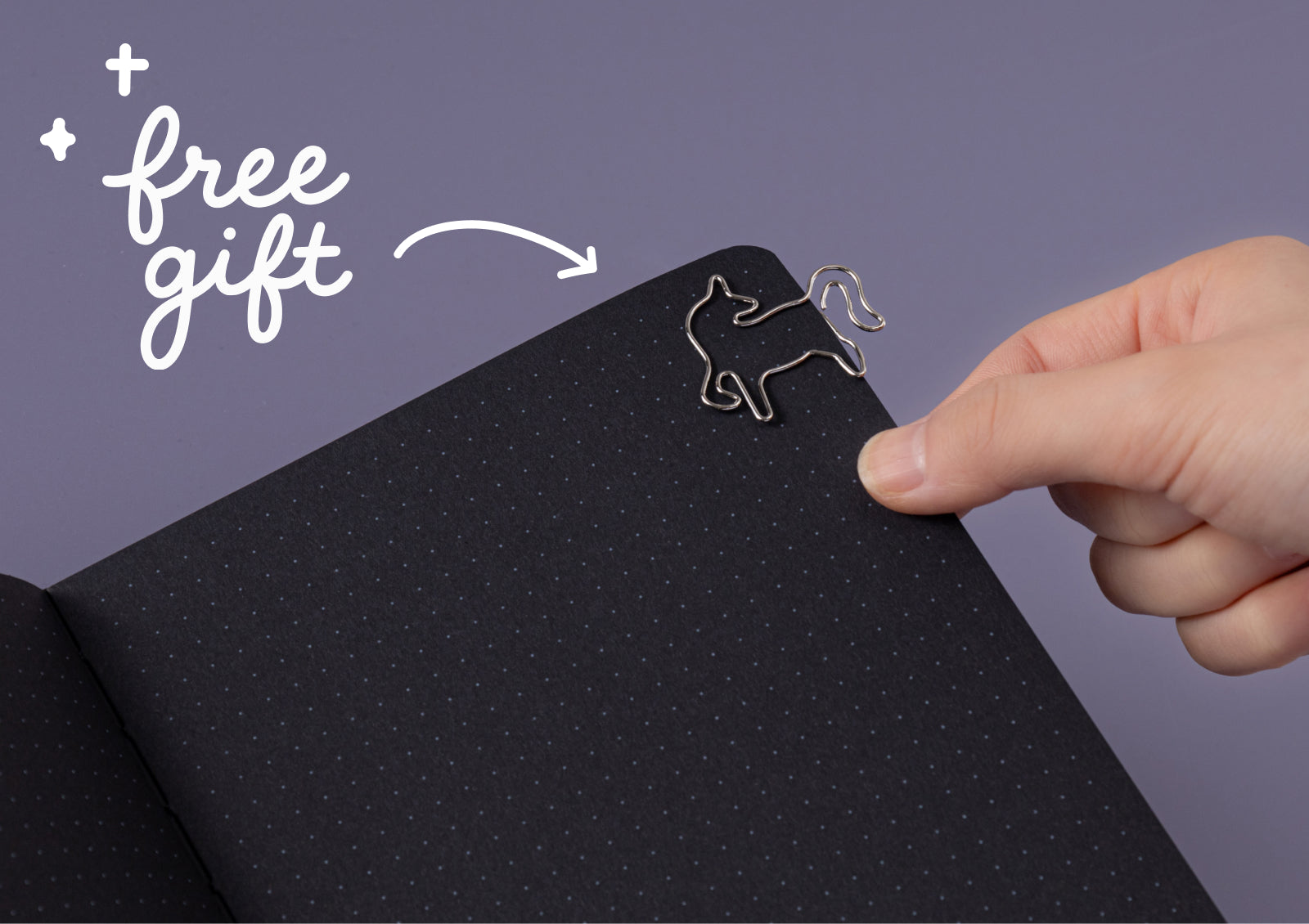 Hands opening the Tsuki Moonflower Magic Lunar Unicorn Notebook black edition, showing dotted pages inside.