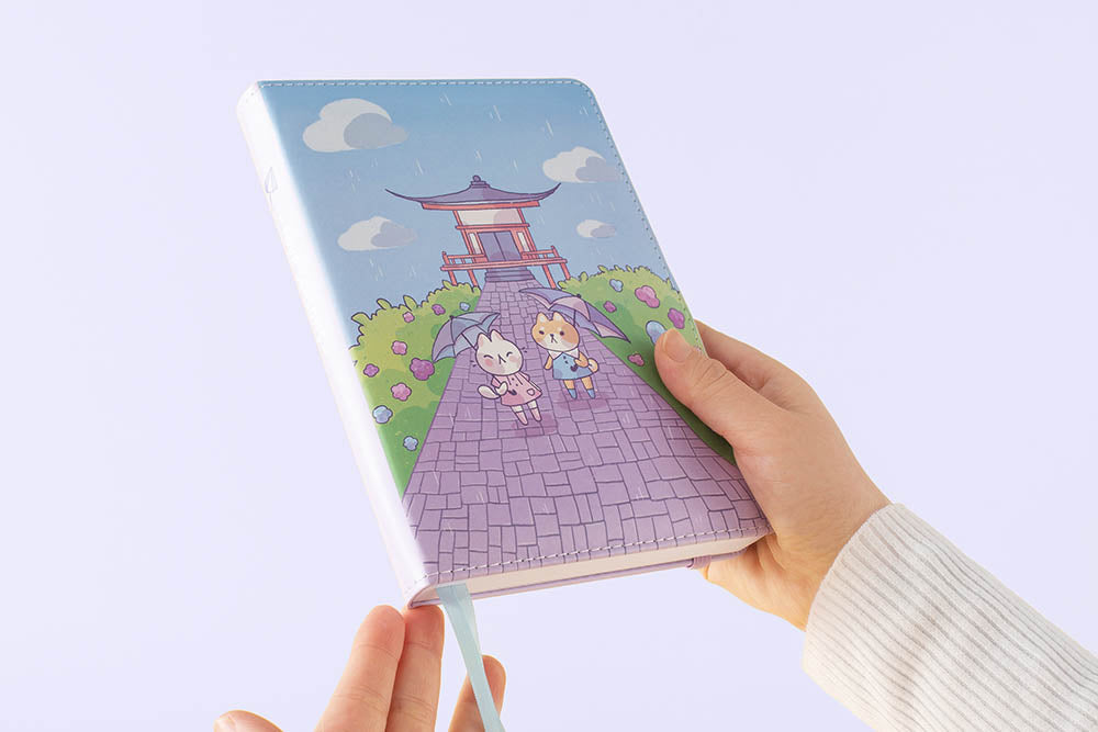 Tsuki Four Seasons: Summer Edition Bullet Journal designed with @milkkoyo held in hands at an angle in lilac background