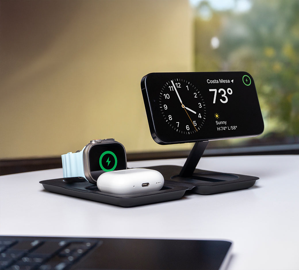 A black charging dock with a phone and Apple Watch charging.