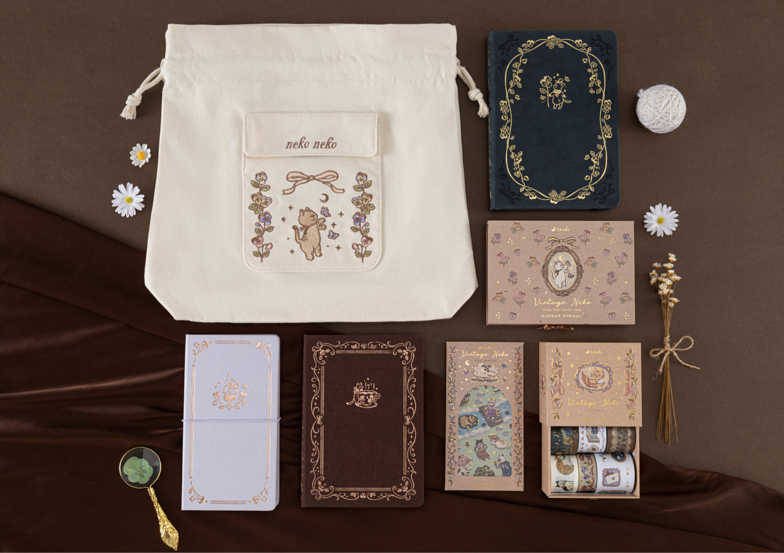 A full product collection flat lay including a canvas bag, multiple journals, the Vintage Neko wooden stamp set, and a washi tape set.