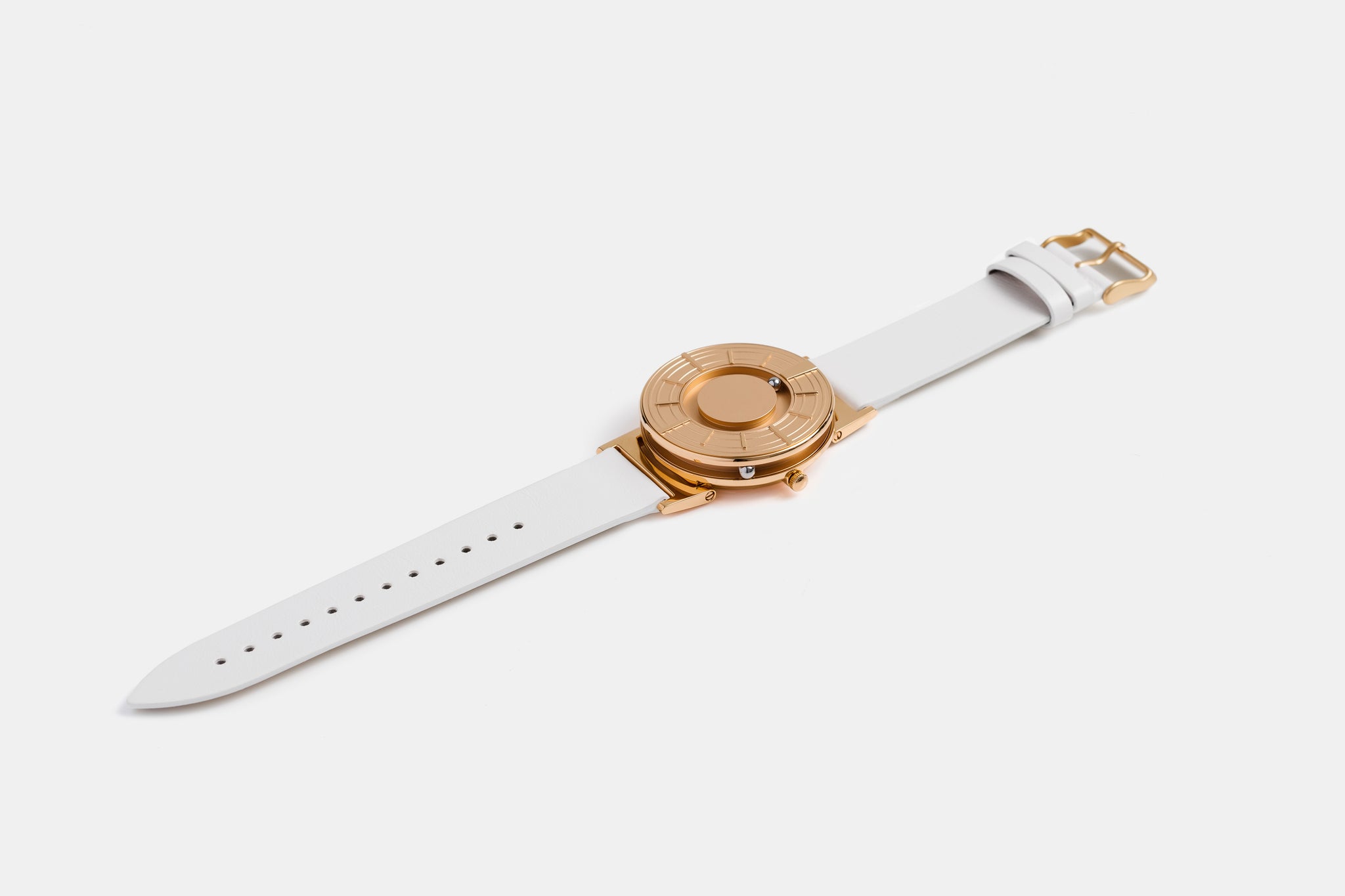 A photo of the watch lying flat on a surface. The recessed track around the outside of the watch face is shown with the hour ball bearing in the track. The raised markers are noticeable from this perspective.