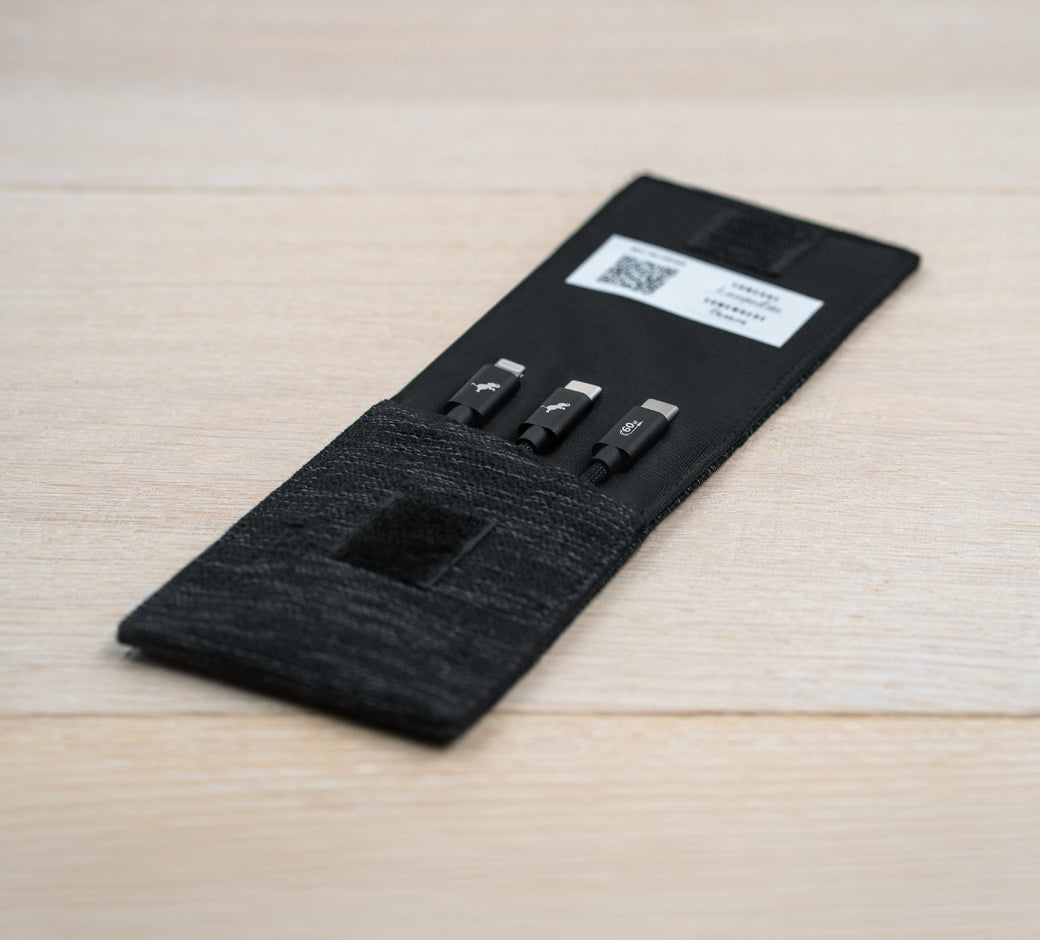 Close-up of a knotted black braided charging cable on a wooden surface.