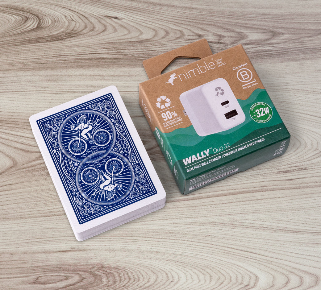 White wall charger charging a smartphone and earbuds with green plant in the background.