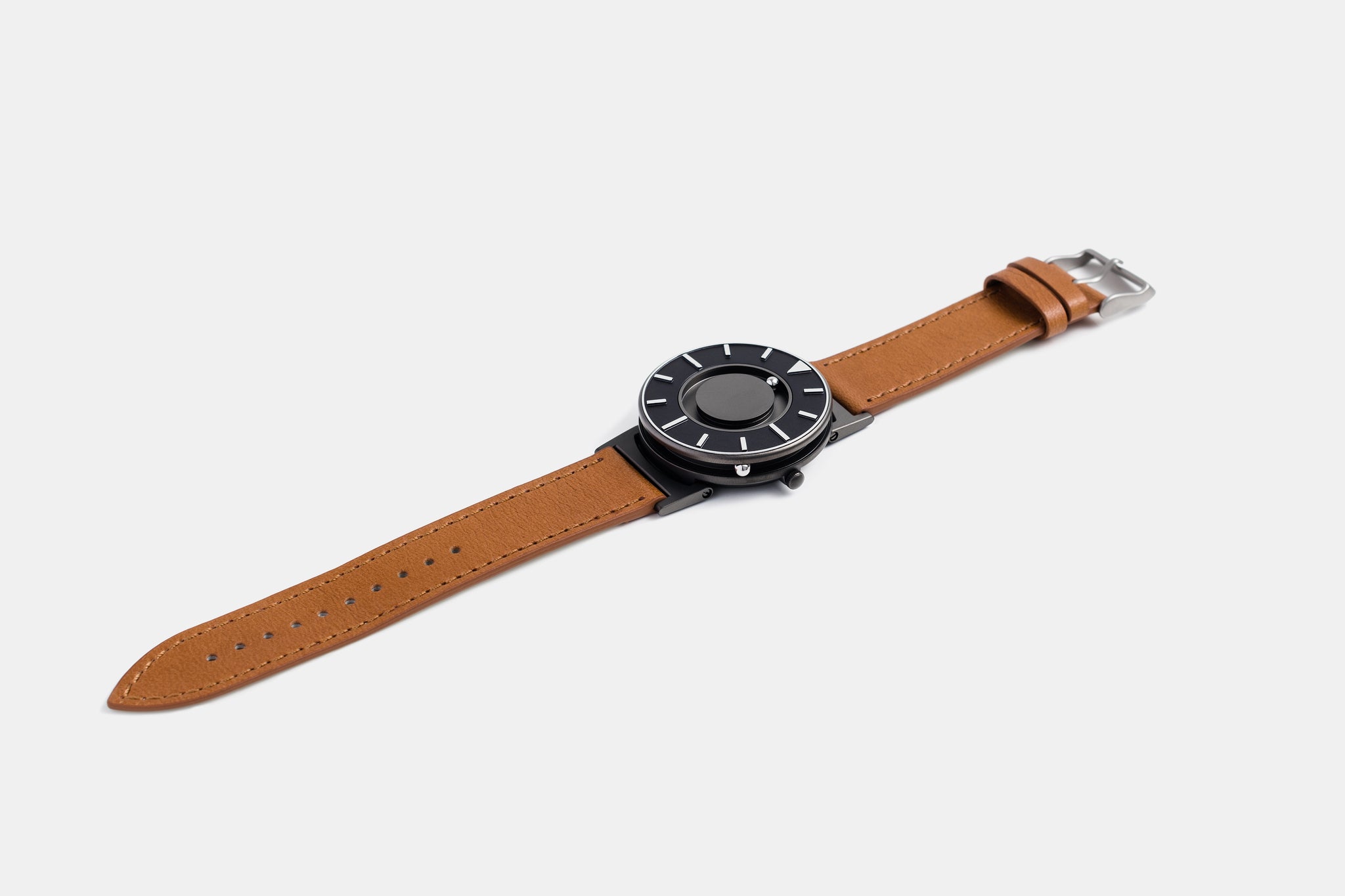 A photo of the watch lying flat on a surface. The recessed track around the outside of the watch face is shown with the hour ball bearing in the track. The raised markers are noticeable from this perspective.