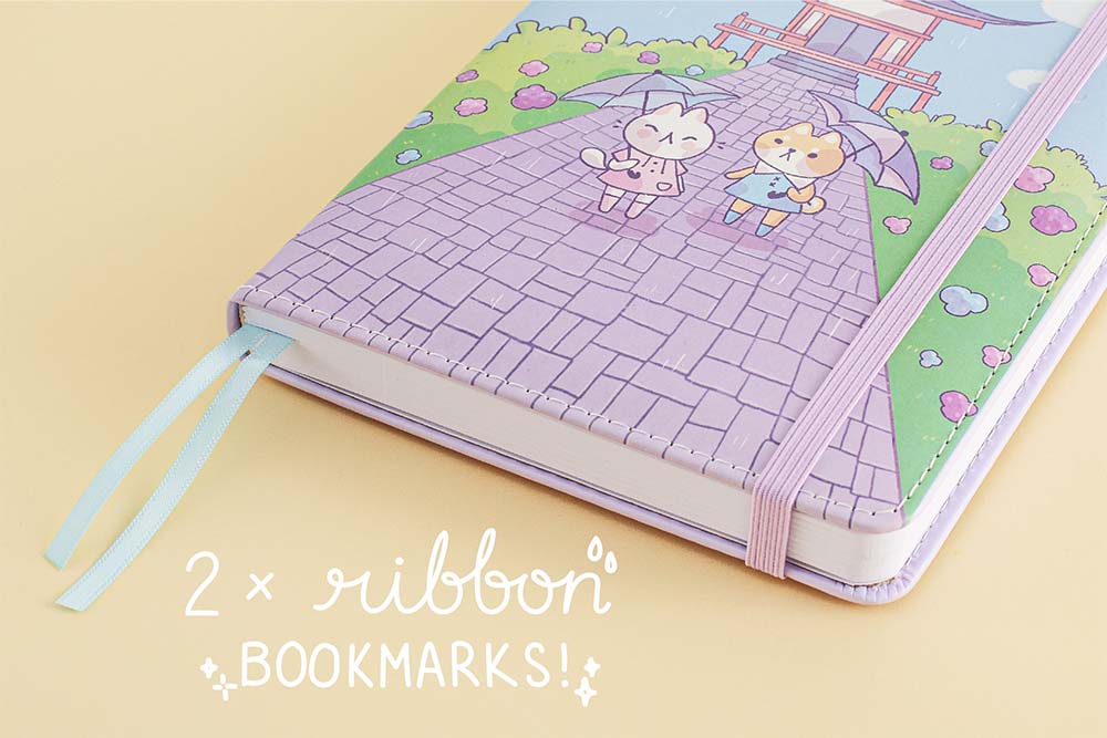 Close up of the front cover of Tsuki Four Seasons: Summer Edition Bullet Journal designed with @milkkoyo with two ribbon bookmarks on honey yellow background