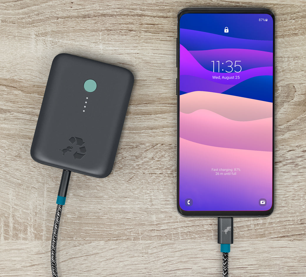 Power bank charging a smartphone with a braided USB-C cable connected.