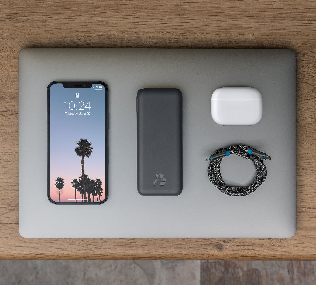 Tablet, phone, and power bank charging together on a wooden surface.