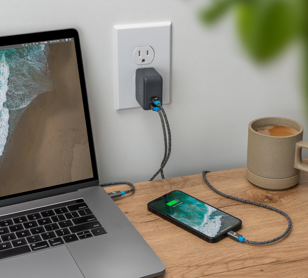 Laptop and phone charging simultaneously using a wall charger, with a coffee mug on the desk.