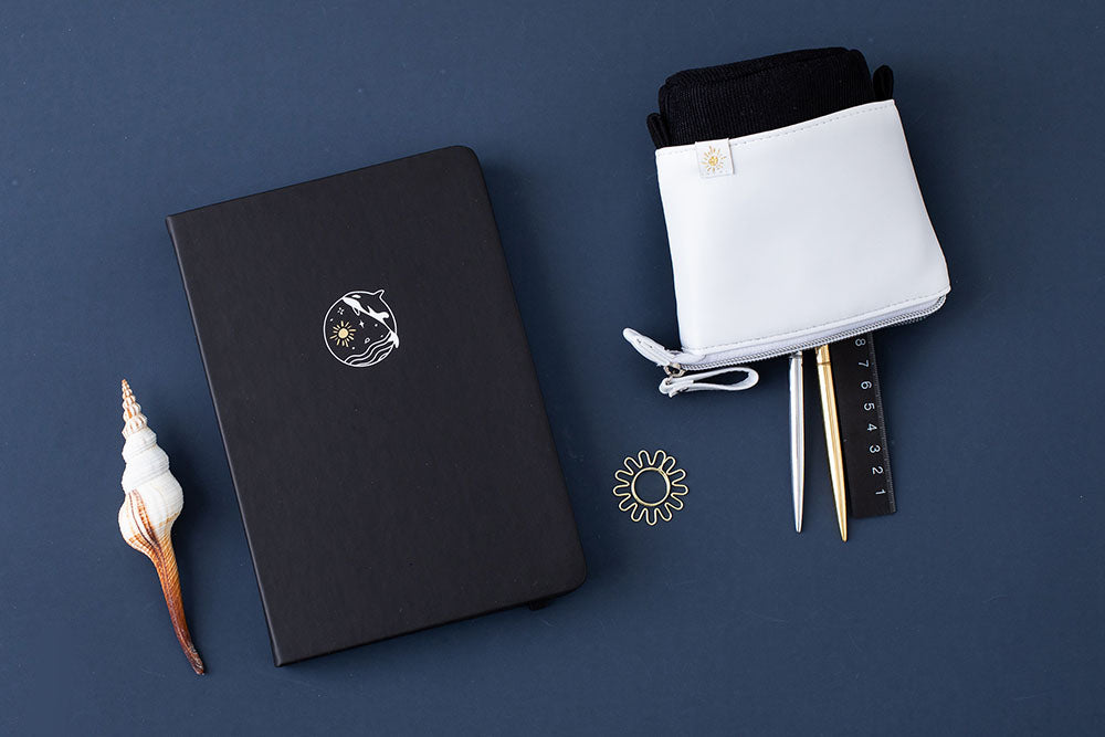 Tsuki Black Paper Limited Edition Hardcover Bullet Journal in Playful Orca with free sunshine bookmark gift with Tsuki Ocean Edition Pop-Up Pencil Case in Orca Black with shell on dark blue background