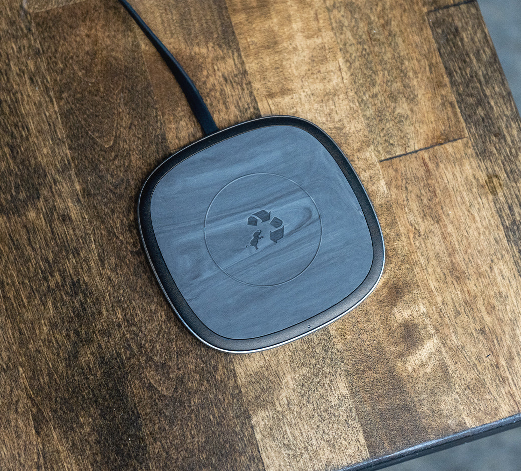 Square marbled black wireless charging pad on a wooden surface with a minimalistic look.