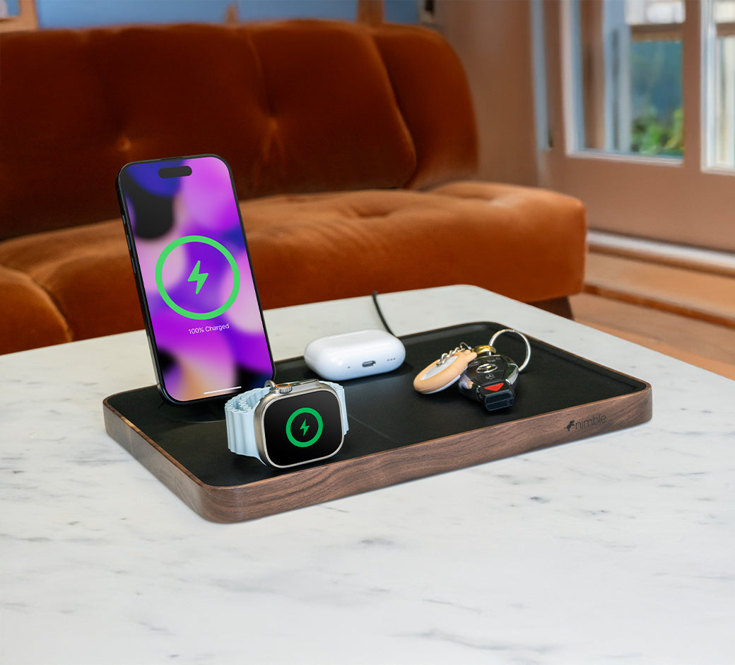 Phone, AirPods, and key fob on a charging tray with phone at full charge.