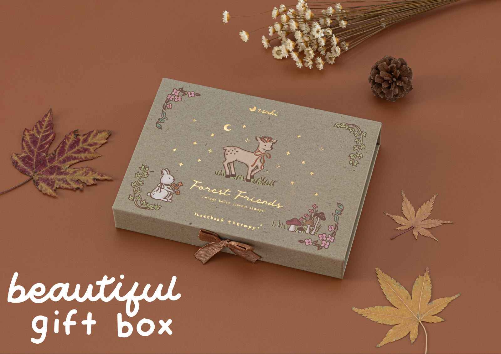 Closed Forest Friends gift box with a deer and bunny illustration, decorated with autumn leaves and ribbon.