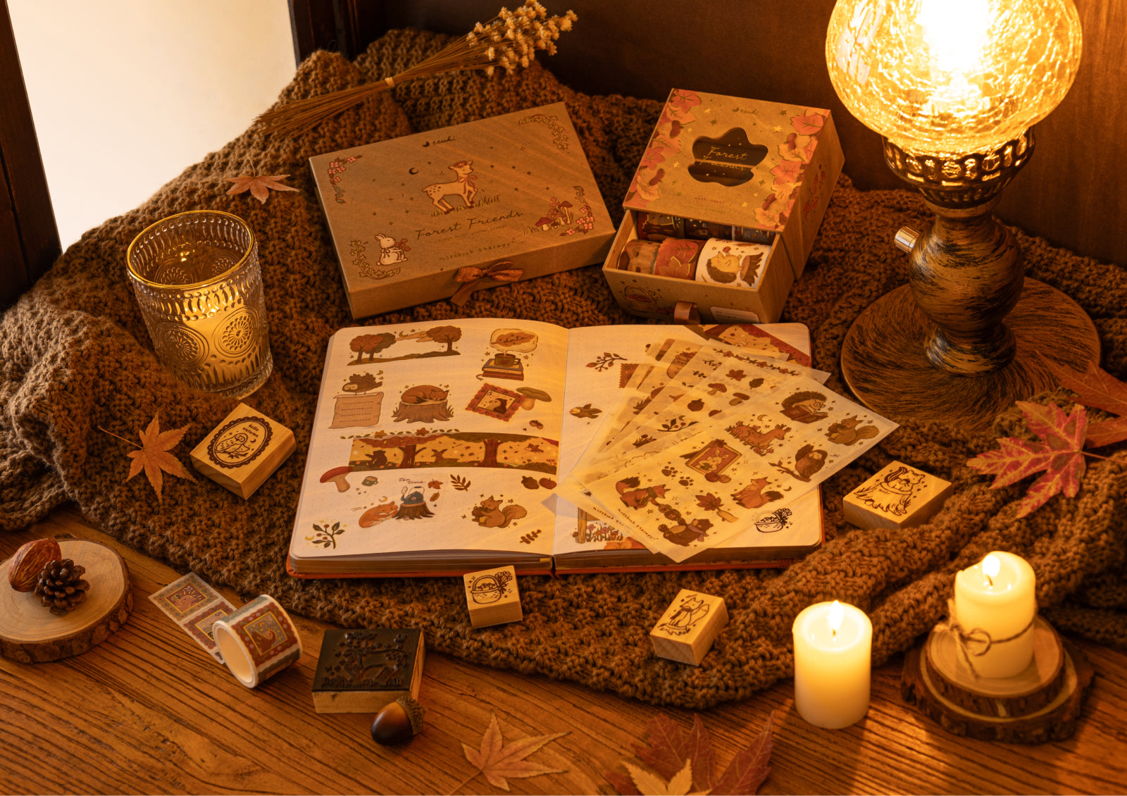 Cozy desk scene with candles, Forest Friends stamps, washi tapes, and sticker sheets arranged around an open journal.