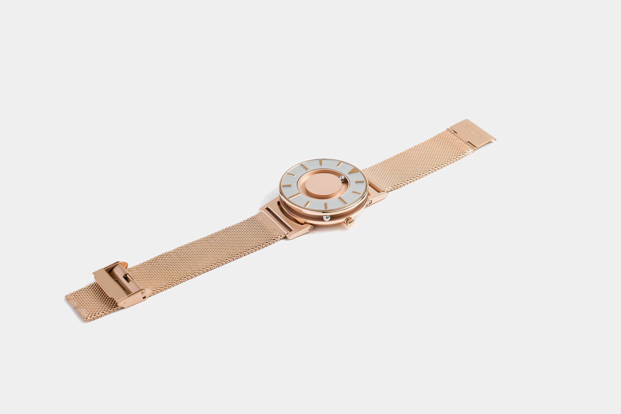 A photo of the watch lying flat on a surface. The recessed track around the outside of the watch face is shown with the hour ball bearing in the track. The raised markers are noticeable from this perspective.