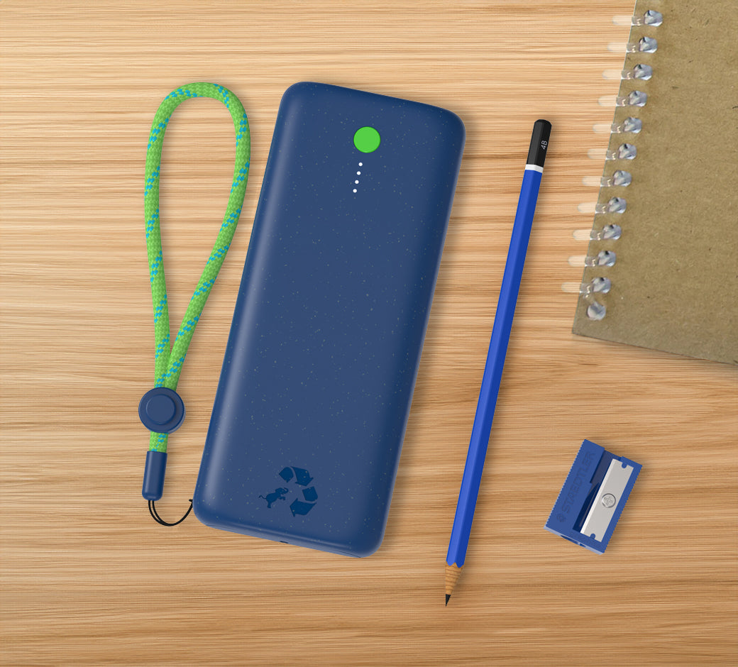 Blue power bank with a green cord on a wooden desk next to stationery.