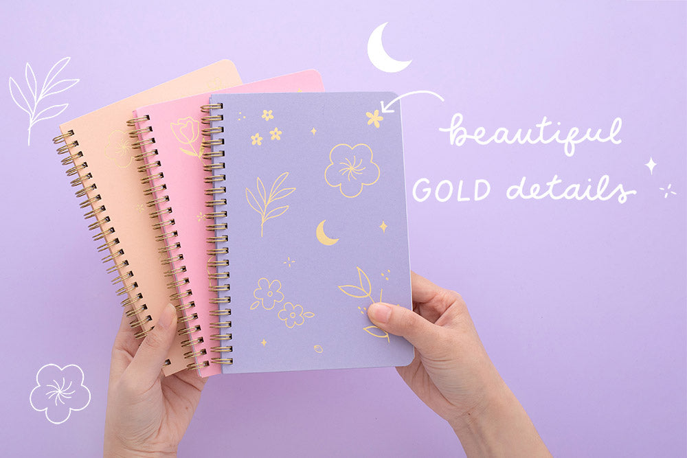 Tsuki Floral collection 3 ringbound bujo held in hands, on lilac background