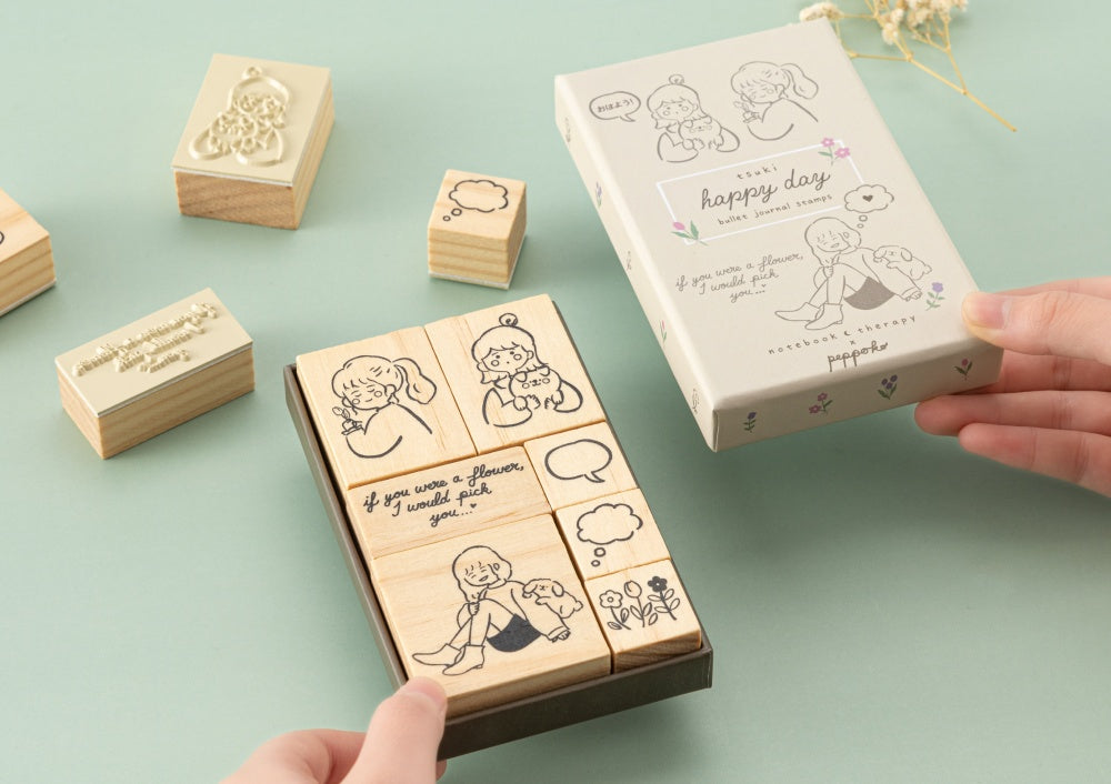 Hands holding Tsuki Happy Day bullet journal stamp box with the lid on the other hand