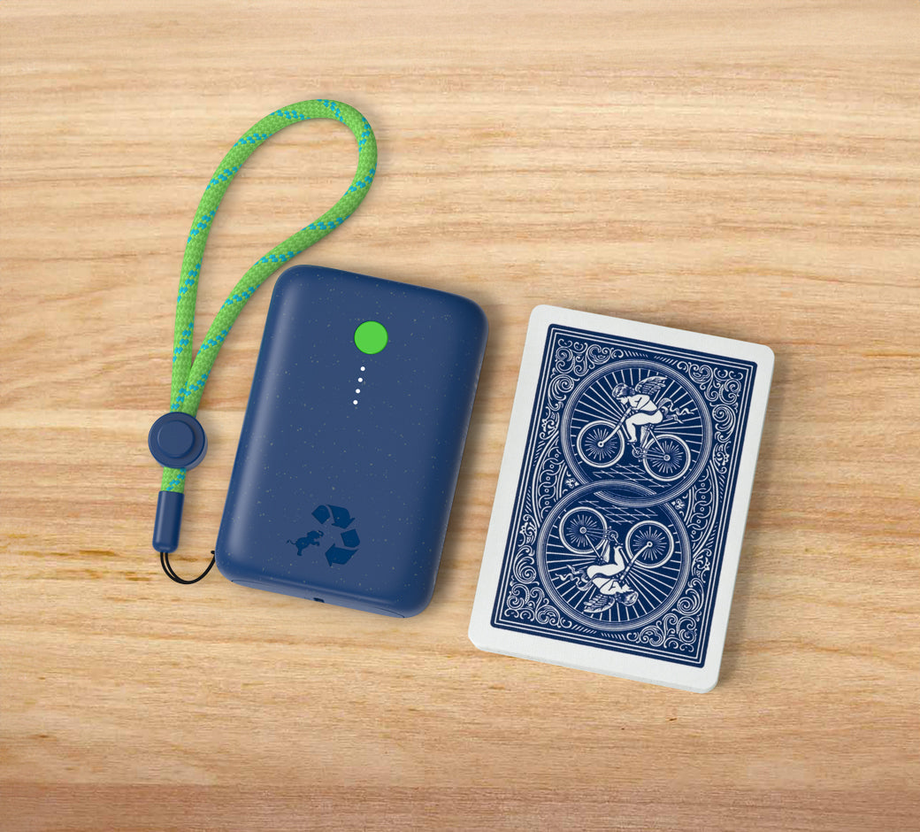 Navy portable charger with green button and lanyard next to playing cards.