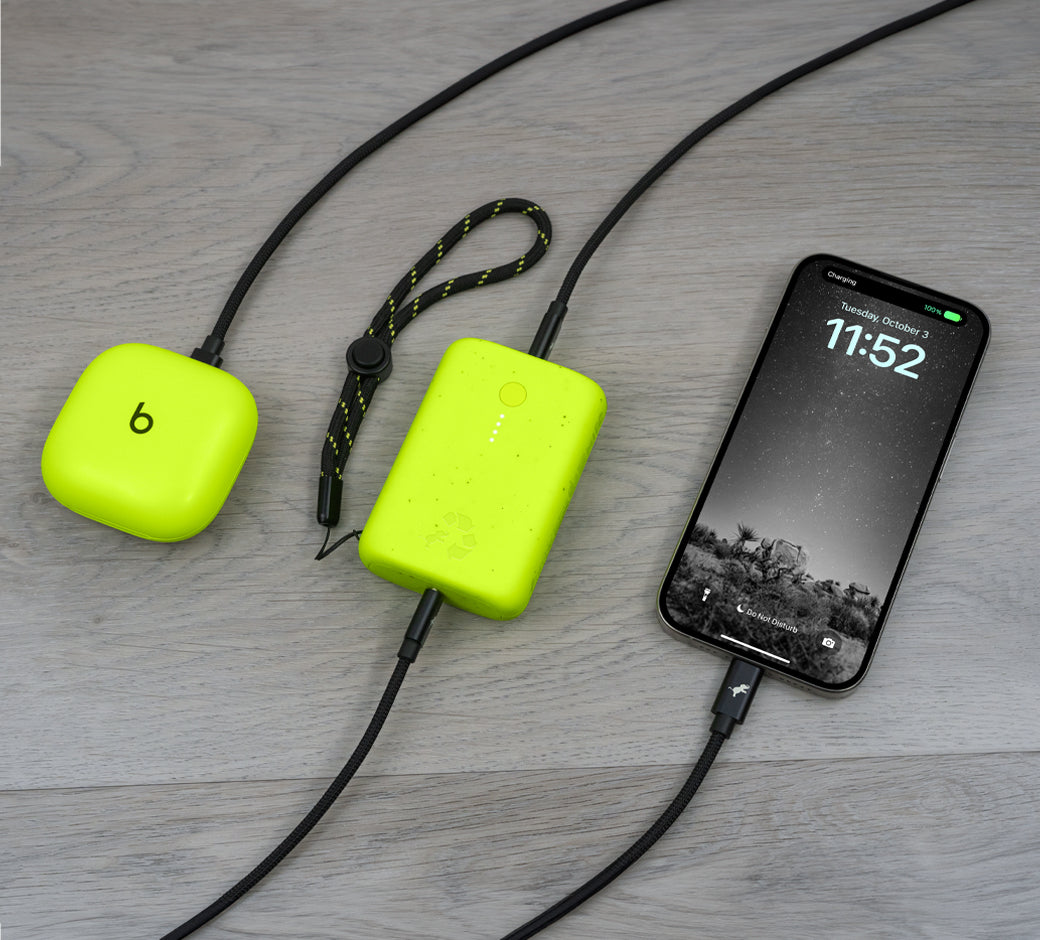 Power bank charging a phone and earbuds with matching cables.