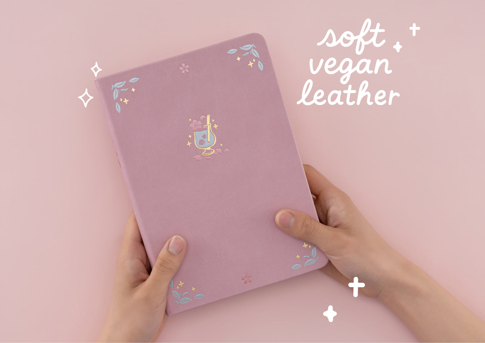 Hands pressing into the soft pink vegan leather cover of the Matcha Bloom notebook to demonstrate its texture.