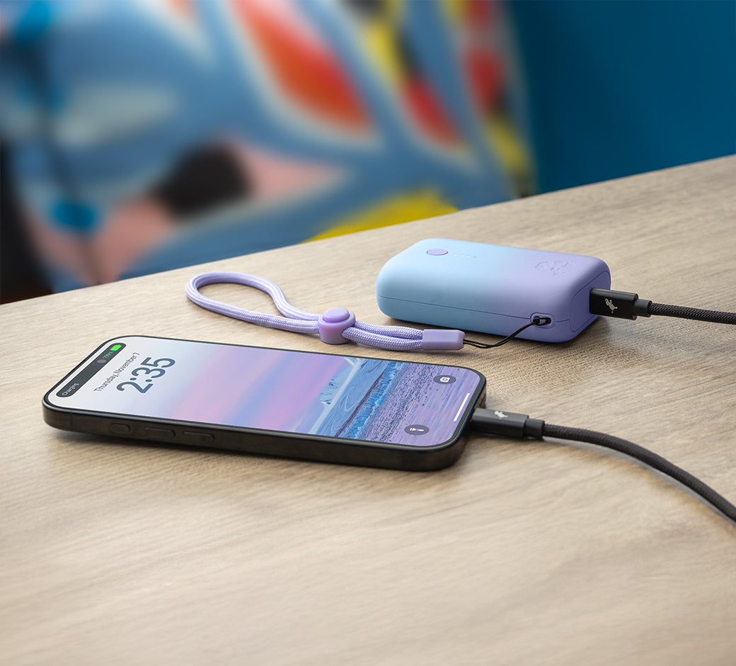 Smartphone connected to a portable charger on a wooden table with colorful background.